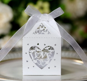 Detail of white laser-cut wedding favor box featuring LOVE heart and silk ribbon