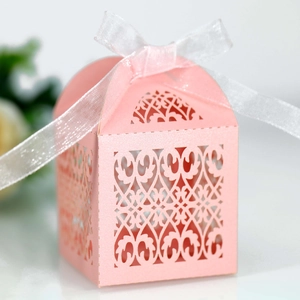 Close-up of pink laser-cut wedding favor box with pearl shimmer finish and white ribbon bow