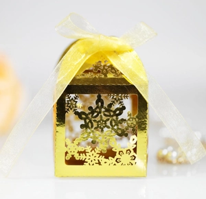 Detail of laser-cut snowflake pattern on golden gift box with a yellow ribbon bow