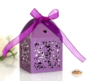 Macro detail of laser-cut purple gift box with floral pattern and satin ribbon bow