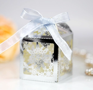 Detail of silver laser-cut snowflake gift box with a light blue satin ribbon bow