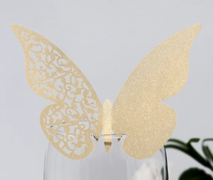 Detailed close-up of golden glitter butterfly place card with intricate laser cutouts on glass
