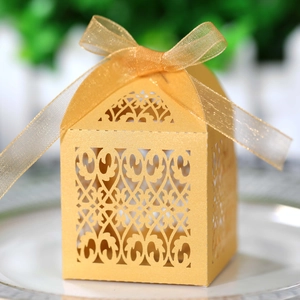 Laser-cut golden pearlescent wedding favor box with intricate hollow pattern and ribbon bow