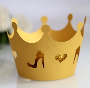 Macro shot of laser-cut golden crown cupcake wrappers with heart and heel patterns