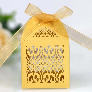 Macro view of laser-cut gold pearlescent paper wedding favor box with ribbon