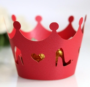 Macro detail of red crown cupcake wrapper with heart and high heel laser-cut patterns