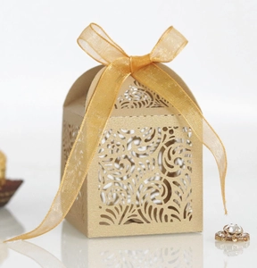 Detail of laser cut floral patterns on a gold wedding candy box with a ribbon bow