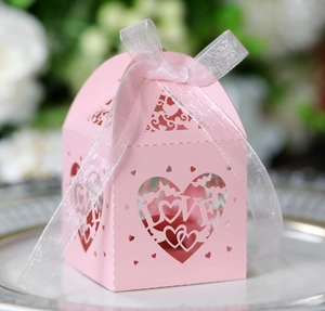 Close-up of pink laser-cut LOVE candy box with a white organza ribbon bow on a ceramic plate