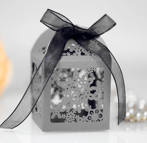 Macro detail of laser-cut snowflake patterns on a pearlescent grey gift box with ribbon