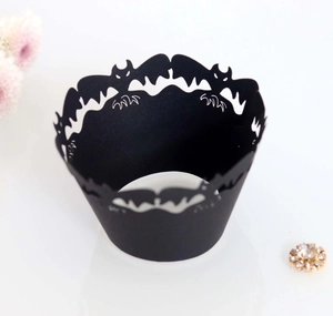 Detail of laser-cut black Halloween cupcake wrappers with hollow bat pattern decorations