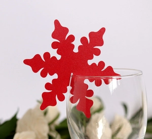 Close-up of laser-cut red snowflake placeholder card on a glass rim for parties