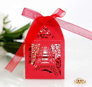 Detail of red laser-cut favor box with Eiffel Tower pattern and elegant ribbon bow