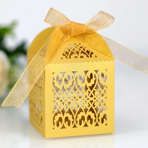 Detail of laser-cut golden candy box with floral patterns and a sheer ribbon bow