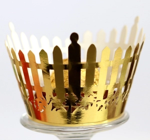 Detailed view of hollowed-out golden picket fence cupcake wrapper with metallic texture