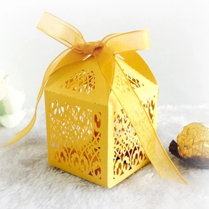 Macro detail of laser-cut floral pattern on yellow paper favor box with ribbon bow