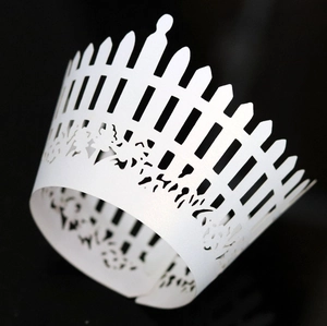 Macro shot of laser-cut white cupcake wrapper with fence and floral lace patterns