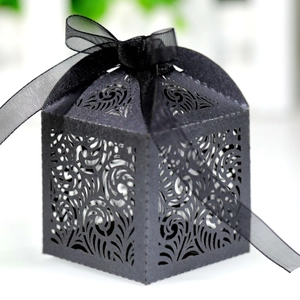 Close-up of elegant black laser-cut wedding favor box with a translucent organza ribbon