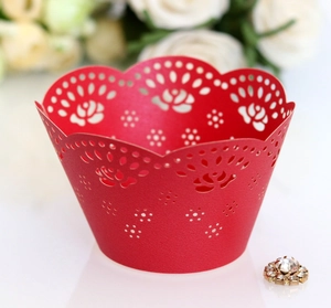 Close-up of laser-cut red paper cupcake wrappers with intricate rose flower patterns
