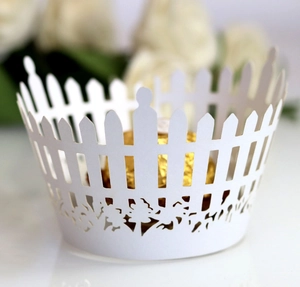 Laser-cut white paper cupcake wrappers with elegant garden fence and tree silhouettes