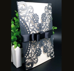 Intricate laser-cut floral wedding invitation set with elegant black ribbon bow