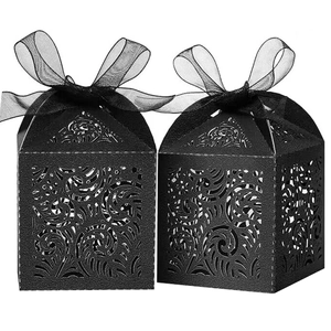 Detail of laser-cut lace pattern on black wedding favor boxes with organza ribbons