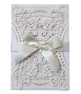 Elegant laser cut wedding invitation with white floral lace cover and satin ribbon bow