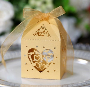 Golden laser-cut candy box with LOVE heart design and organza ribbon on porcelain plate