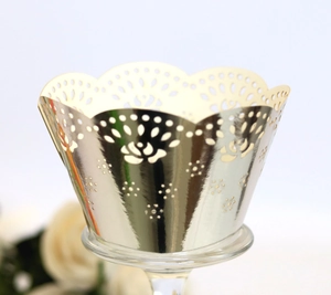 Macro detail of laser-cut gold cupcake wrapper with rose patterns and lace edges