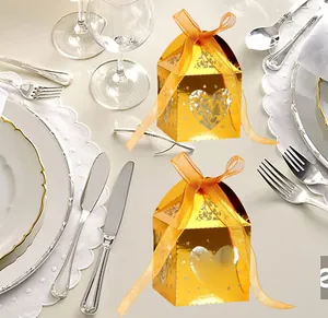 Close-up of golden hollow heart wedding favor boxes with LOVE text and orange ribbon bows