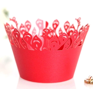 Close-up of red laser-cut cupcake wrapper with intricate floral and peacock patterns
