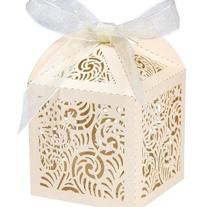 Detail of laser-cut off-white wedding favor box with swirl pattern and white ribbon bow