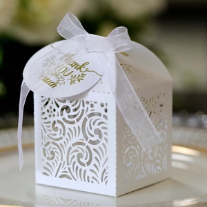 Detailed laser-cut white wedding favor box with a silk ribbon and a gold thank you tag