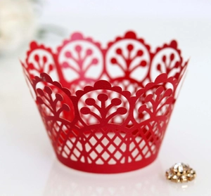 Detailed close-up of red laser-cut cupcake wrappers with crown patterns for wedding decor