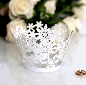 Detail of white laser-cut cupcake wrapper with snowflake patterns and elegant decor
