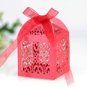 Intricate laser-cut red favor box with vine patterns and red organza ribbon bow