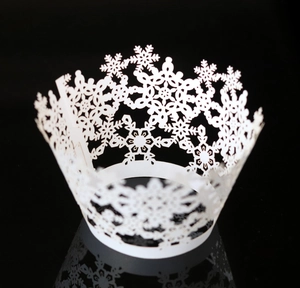 Macro detail of laser-cut white snowflake lace cupcake wrappers for winter party decor