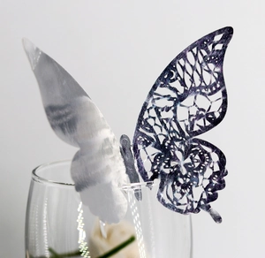 Silver laser-cut butterfly place card clipped onto a glass rim for elegant table decor