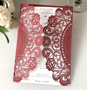 Detail showing deep red laser-cut floral wedding invitation with elegant script typography