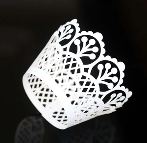Close-up of laser-cut crown cupcake wrapper with intricate white mesh pattern