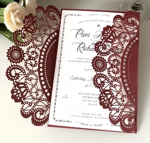 Detail of laser-cut burgundy lace wedding invitation with white floral interior card