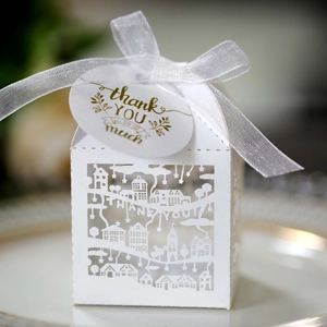 Detail of white laser-cut candy box with thank you tag and ribbon for wedding favors