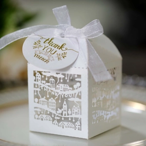 Macro shot of white laser-cut 'THANK YOU' gift box with delicate house pattern and ribbon