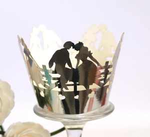 Close-up of golden laser-cut cupcake wrappers with romantic kissing couple silhouette