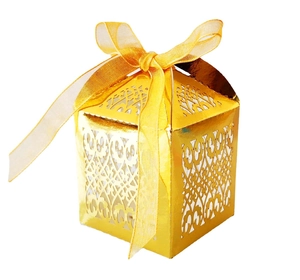 Close-up of golden laser-cut wedding favor box with intricate patterns and ribbon