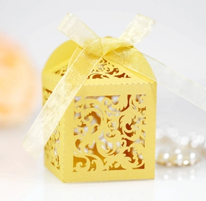 Detail of yellow laser-cut gift box with intricate vine patterns and organza ribbon