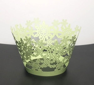 Detail of laser-cut light green cupcake wrapper with intricate snowflake patterns
