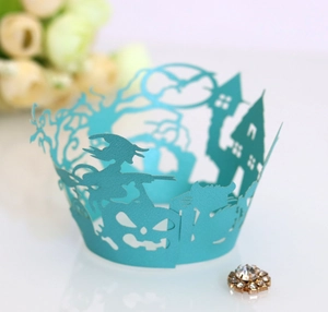 Macro detail of laser-cut teal cupcake wrapper with witch, pumpkin and castle motifs