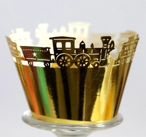 Macro shot of laser-cut reflective gold cupcake wrapper with train silhouette design