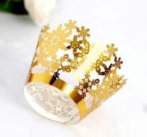 Macro shot of gold laser-cut snowflake hollow lace cupcake wrapper with metallic finish