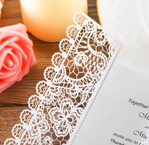 Detailed macro view of laser-cut lace pattern on white pearlescent wedding invitation card